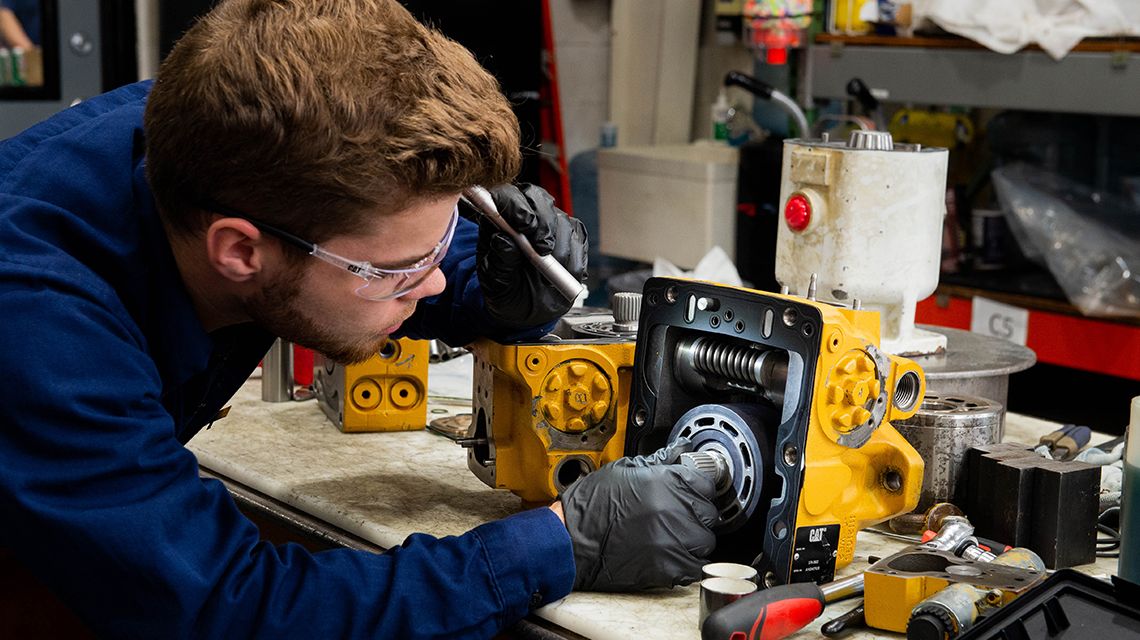 Man inspecting mining machine parts with a flashlight