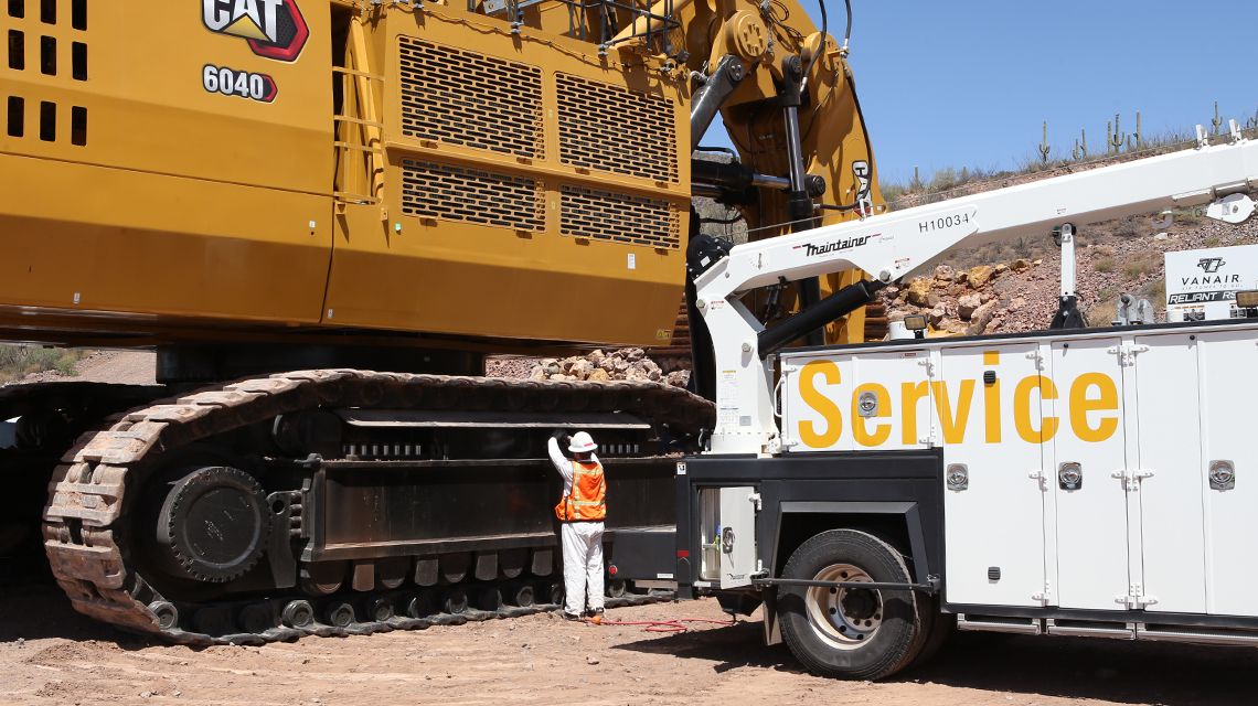 Service technician inpecting undercarriage on mining large excavator