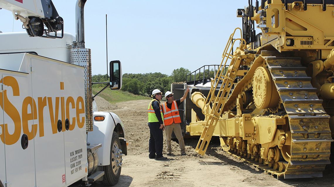 Two men beside each other discussing the mining large dozer next to them