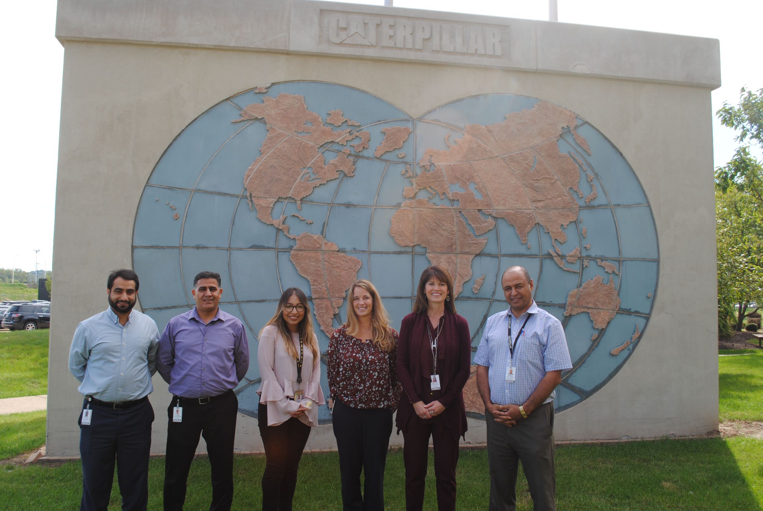 Grupo de funcionários posando em frente a um mapa-múndi.