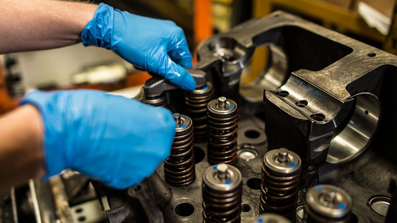 gloved mechanic working on a cat truck engine