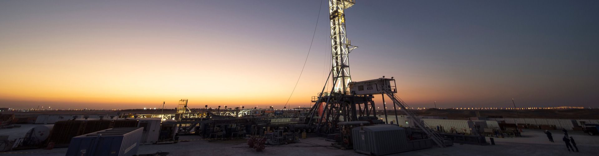 Wide shot of a drilling site at sunset