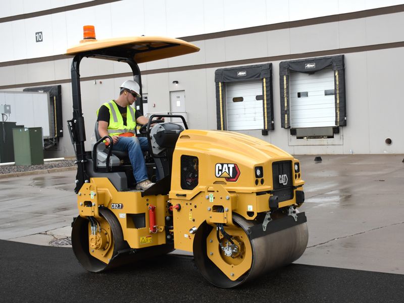 CB2.7 tandem vibratory roller compacting asphalt in a parking lot.