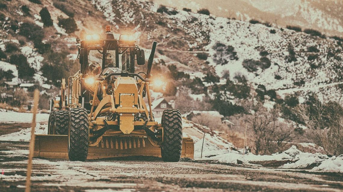 Motor grader flattening land on jobsite