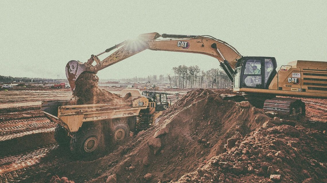 Cat excavator dumping dirt into truck | Payload