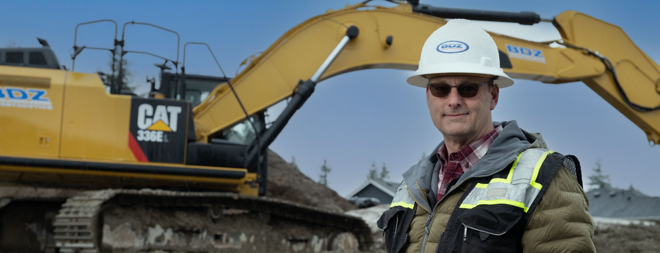 Brandon Jensen, president of BDZ Construction, stands by an excavator on a jobsite