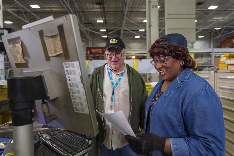 Woman and man working together at a computer in a manufacturing facility. 