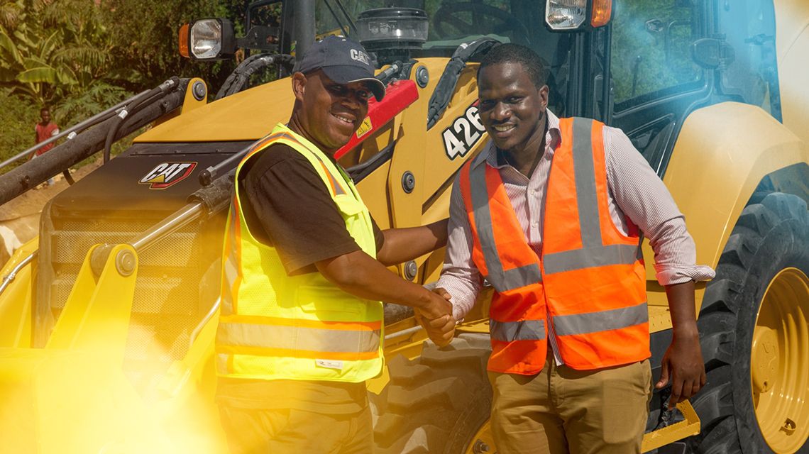 Two men shaking hands in front of a 426 backhoe loader