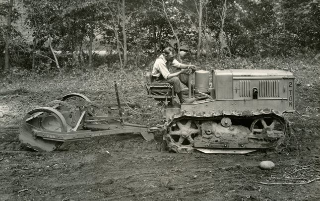 Homem dirigindo um trator antigo em 1928