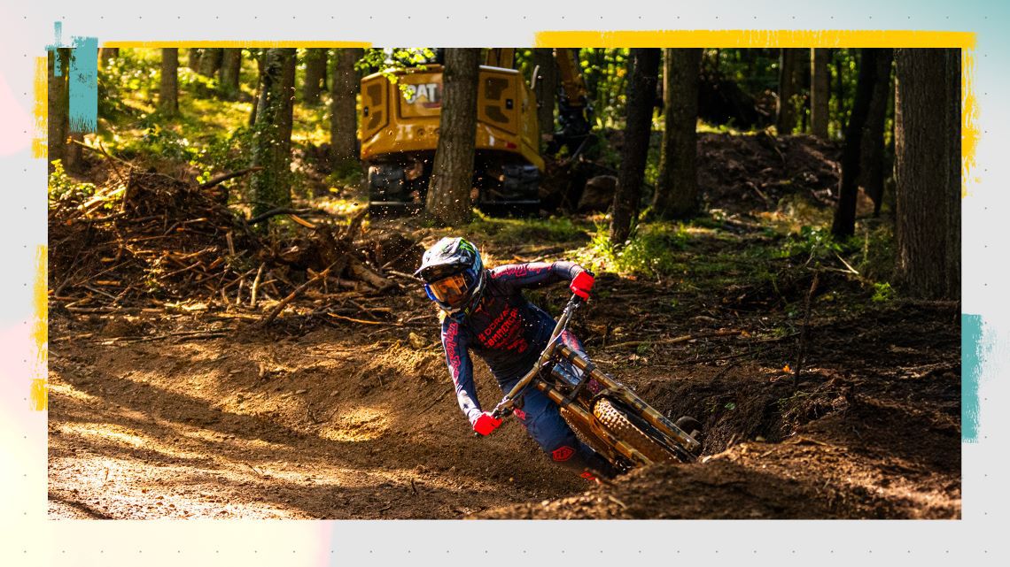 Camille Balanche riding a mountain bike in front of a Cat machine
