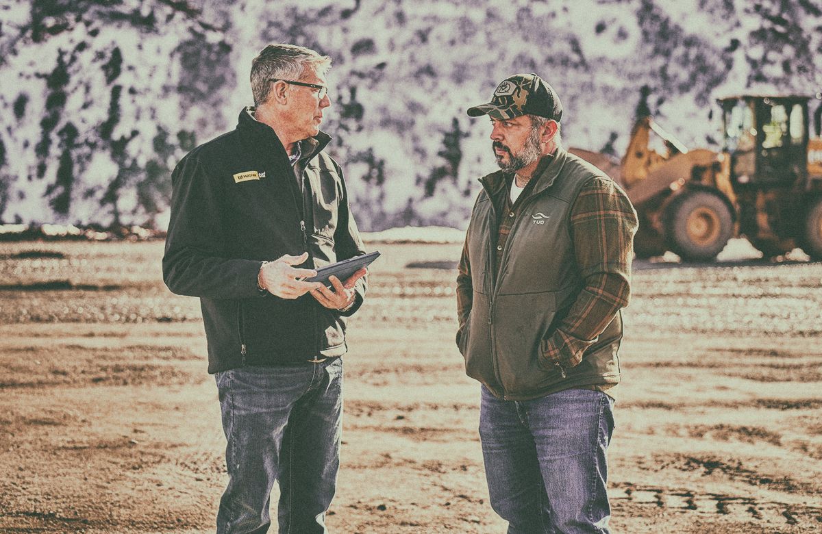 Two people talking to each other with a Cat Wheel Loader in the background