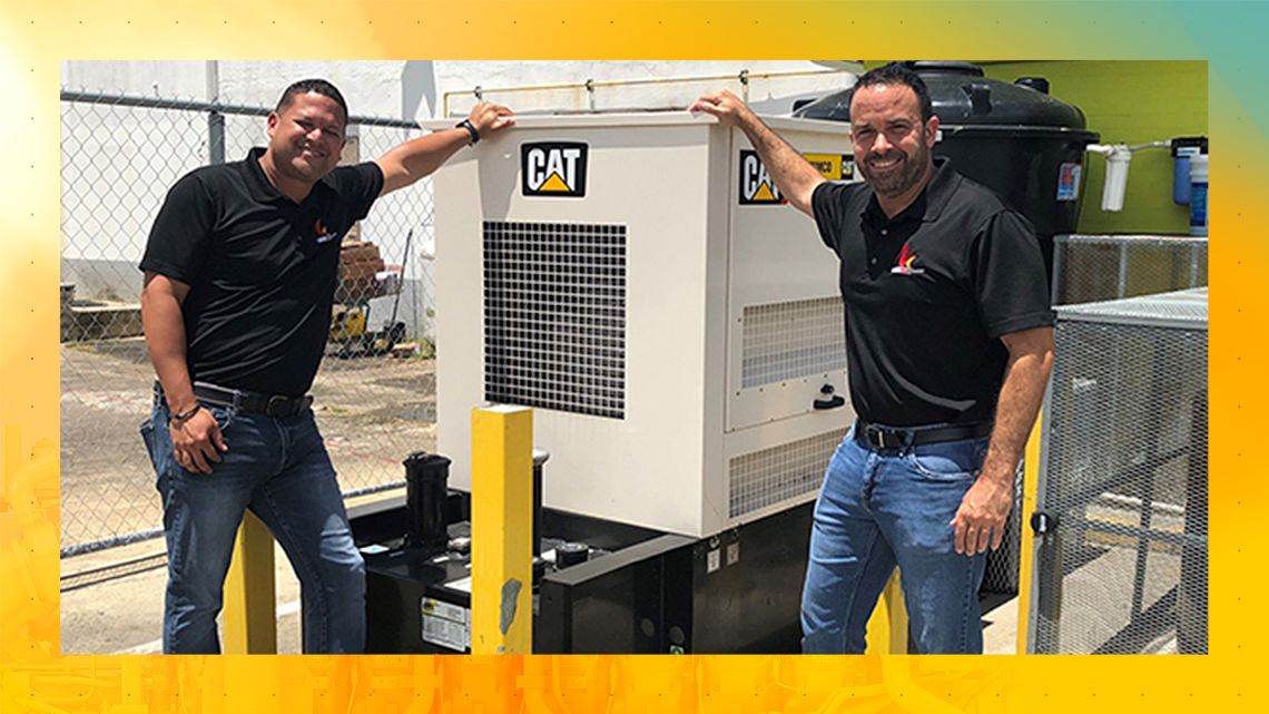 2 men smiling in front of a Cat generator