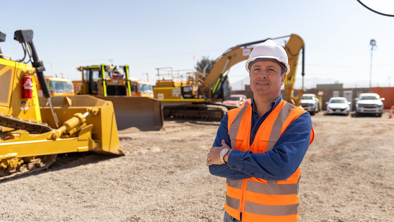 Male customer using Ipad with Excavator working in the background
