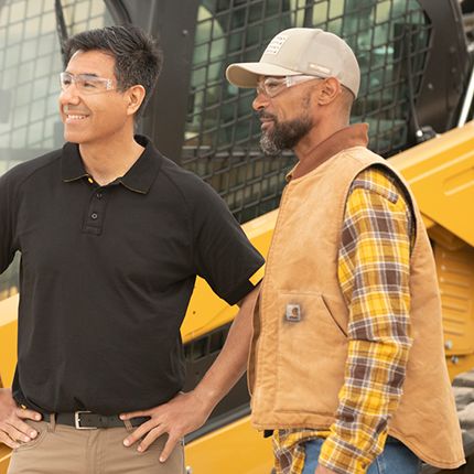 Two men looking off in distance with machinery in background