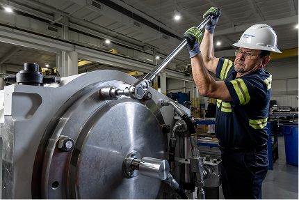 Man in personal protective gear working on frac pump