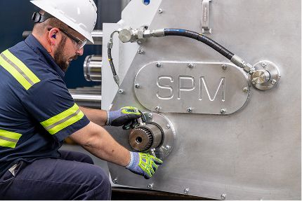 Man kneeling down to work on a well service pump