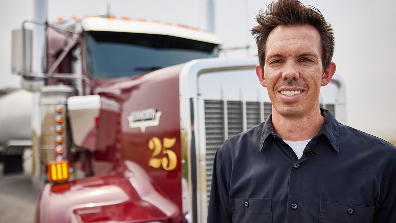 driver posing for a picture in front of a truck