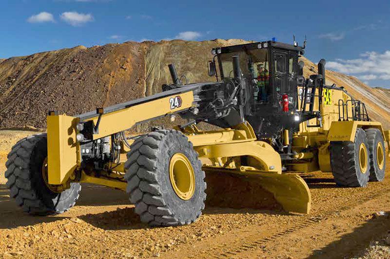 24 motoniveladoras estacionadas en un camino de tierra nivelado