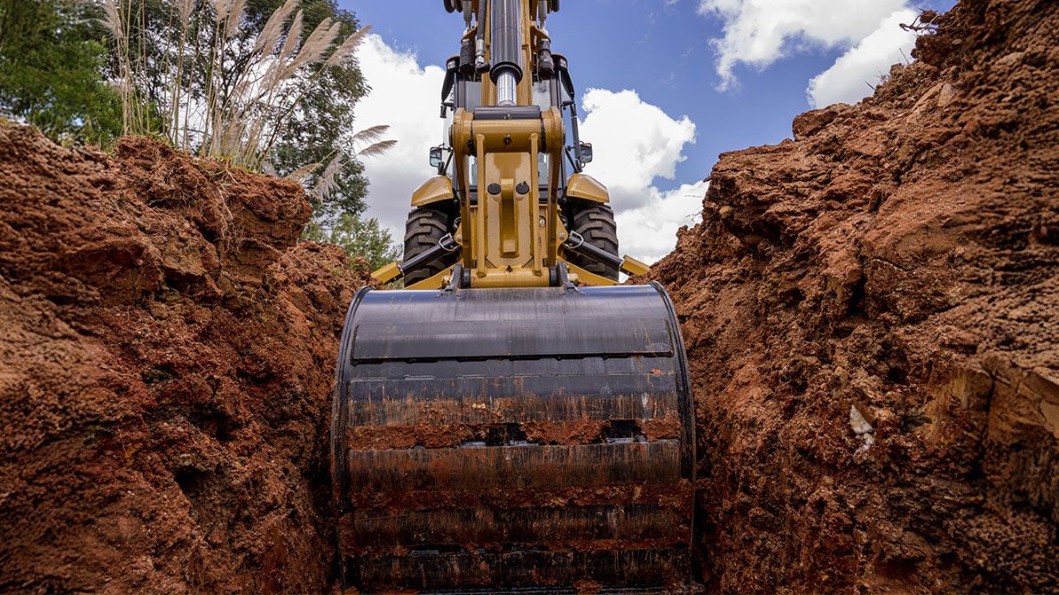 retroexcavadora utilizando un accesorio de cubo para despejar tierra