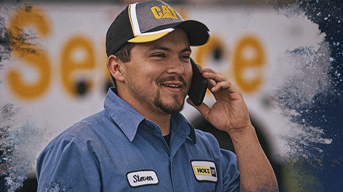 Man talking on a cell phone in front of a Cat Service vehicle