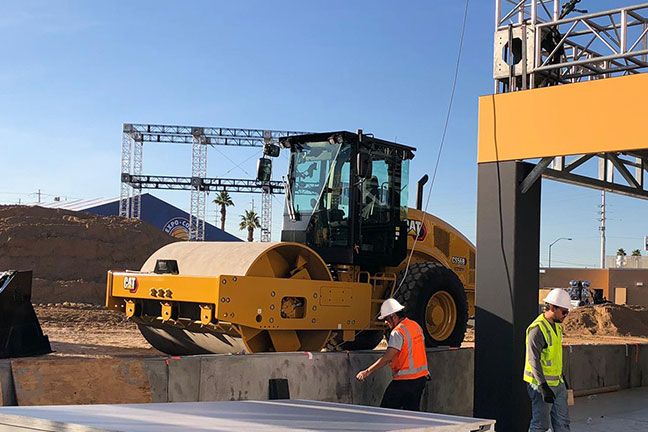 Un compactador de suelo vibratorio en un sitio de construcción rodeado de trabajadores de la construcción