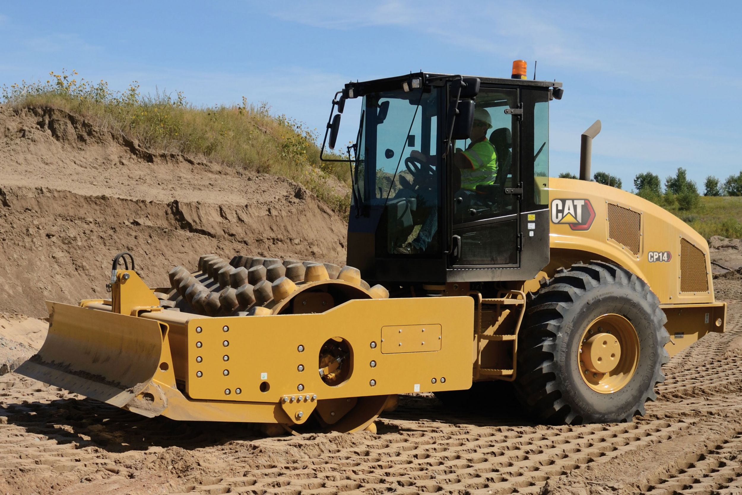 Una toma de un compactador de suelo vibratorio CP14 trabajando en la tierra.