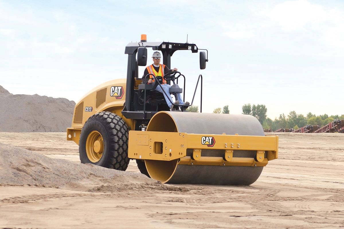 Trabajador de construcción en una compactadora de suelo vibratoria trabajando en un camino de tierra