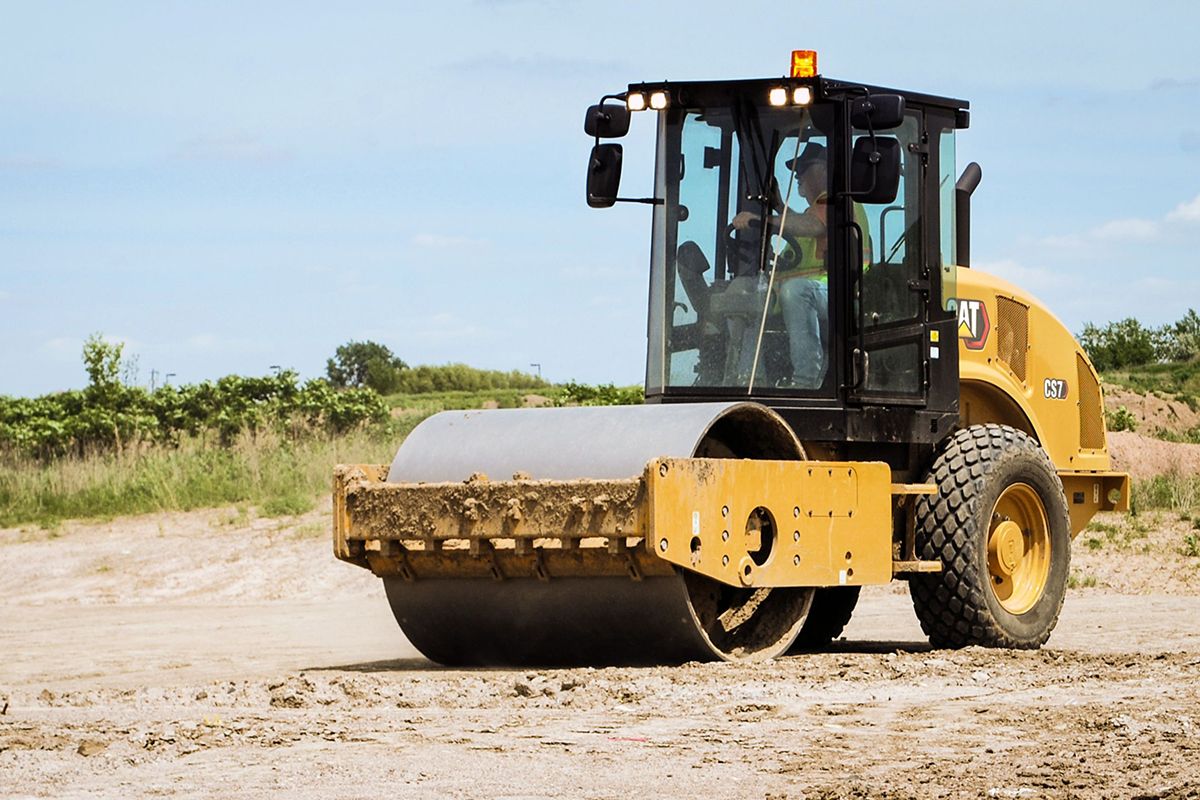 Hombre en compresora de suelo vibratoria CS7 en el campo