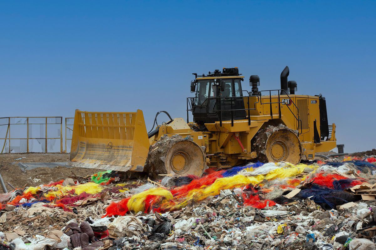 Un compactador de basura atravesando un vertedero limpiando basura
