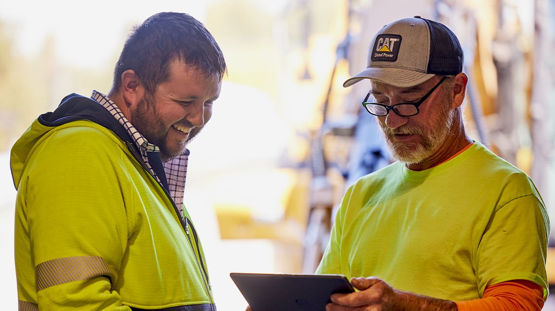 2 people in bright yellow outerwear viewing a tablet