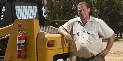 Man posing in front of Cat equipment
