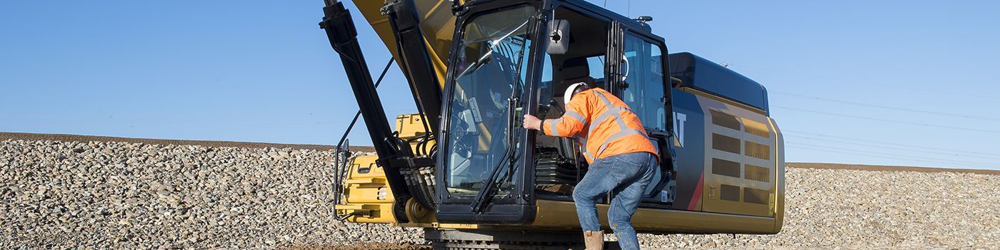 man climbing loader steps into Cat machine cab