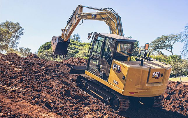 Miniescavadeira Cat® 307 with a bucket attachment operating on dirt