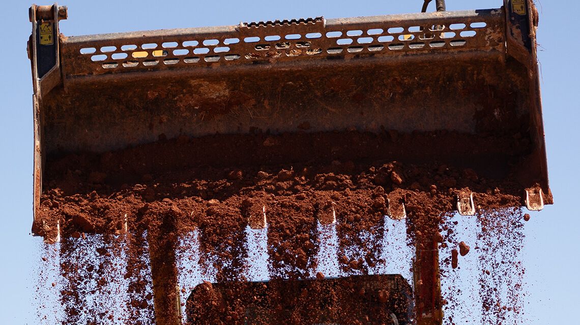 Excavator dumping dirt with ground engaging tool system on bucket