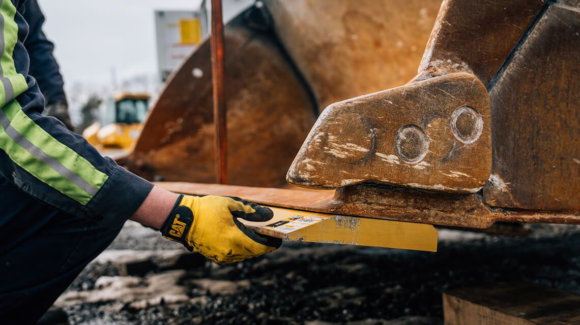 worker making sure an attachment is properly fixed to the bucket of a machine
