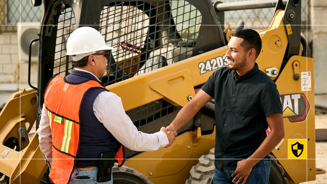 dois homens apertando as mãos perto da minicarregadeira Cat 242D3