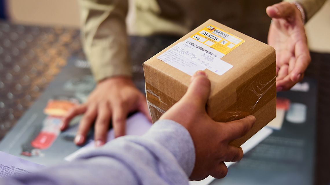 close up of a hand passing a Cat bearing part box to someone else