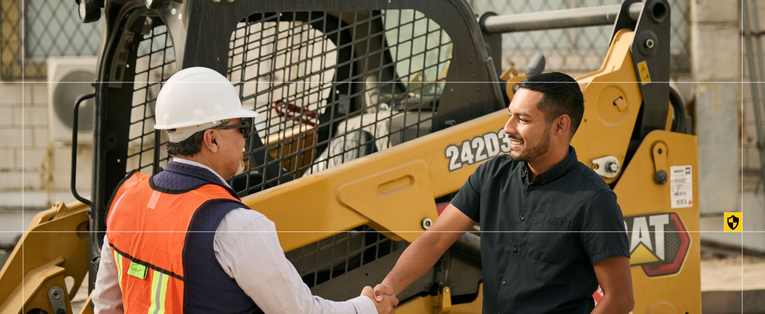 two men shaking hands near Cat skid steer loader 242D3
