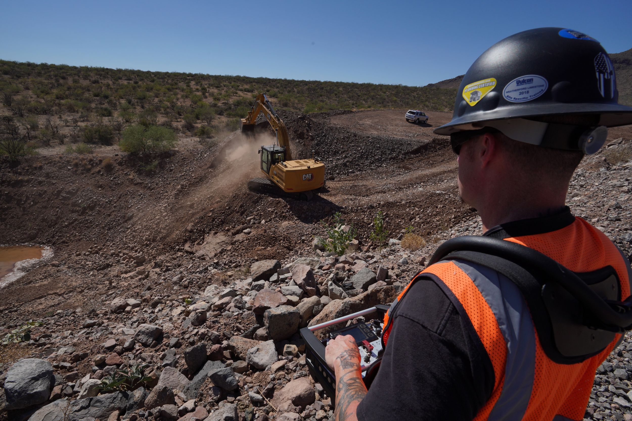 Man operating Cat excavator by remote
