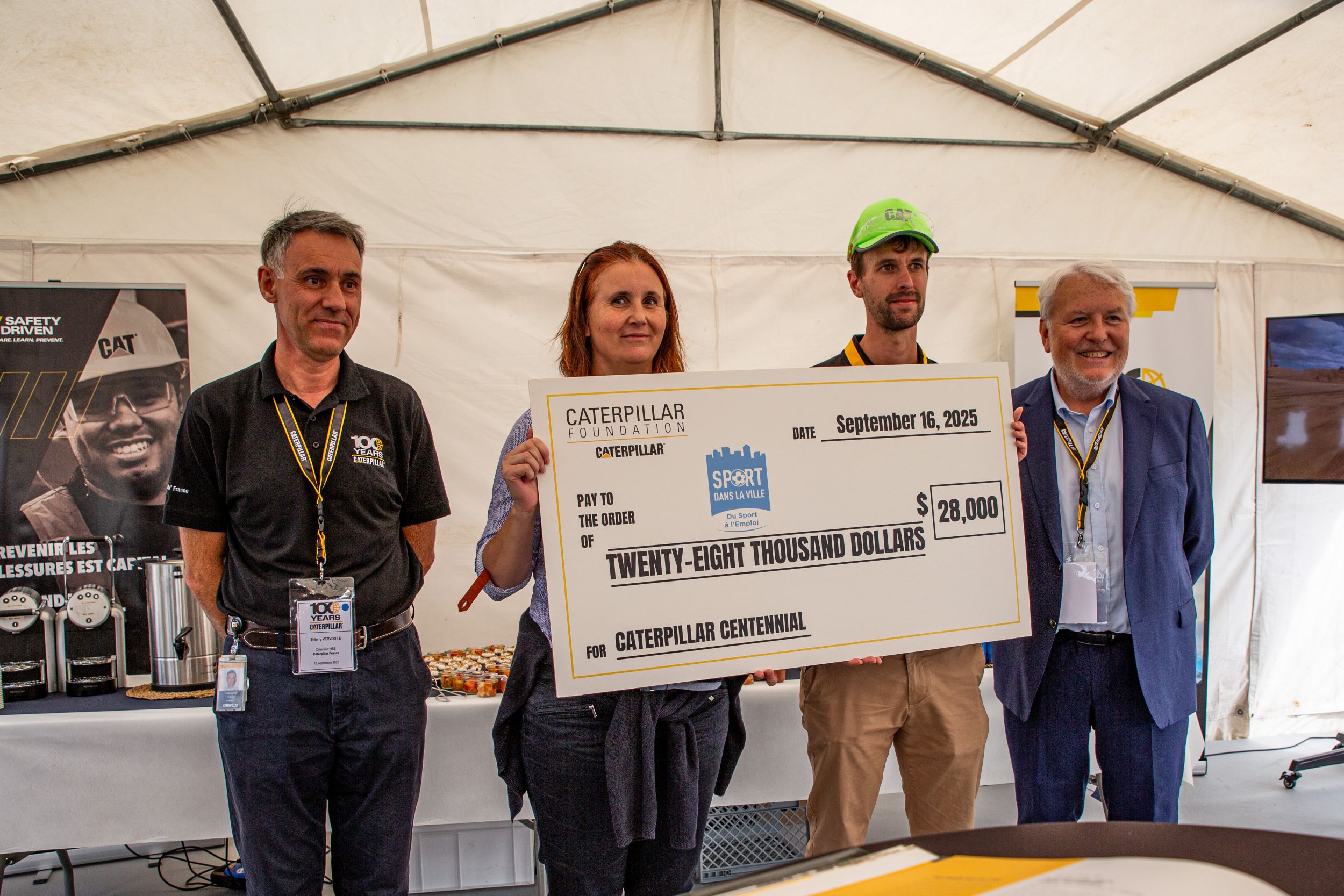 Four people holding a large check to present to a community organization.