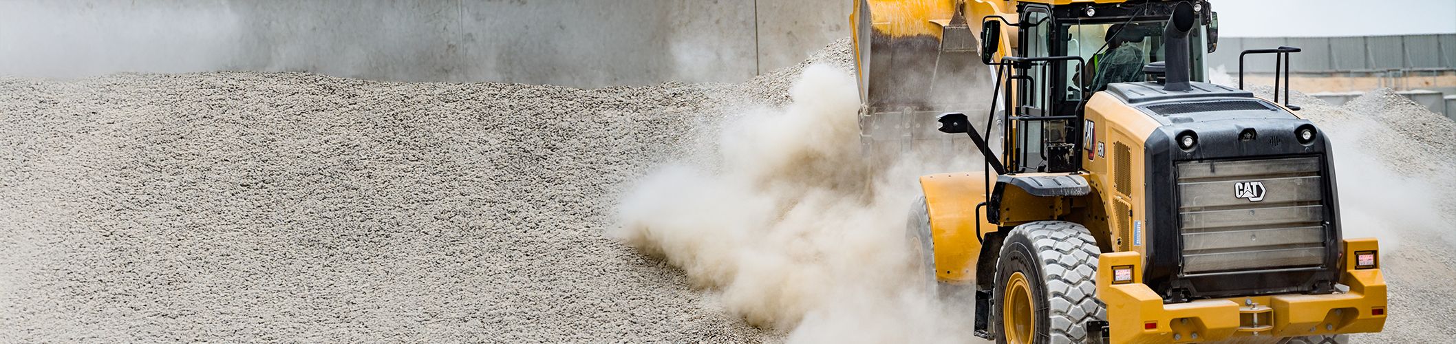 Una pala gommata Cat® durante un sollevamento terra con raggi di sole grafici