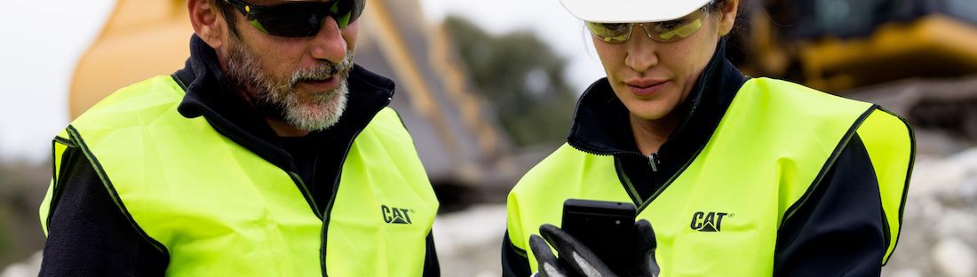 men in safety vests looking at phone