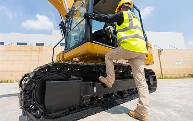 Operador entrando na cabine da escavadeira