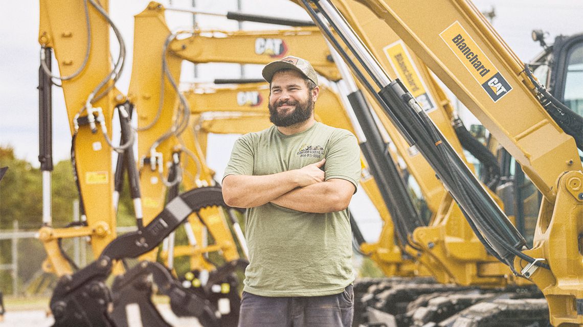 Man standing in front of mini excavators