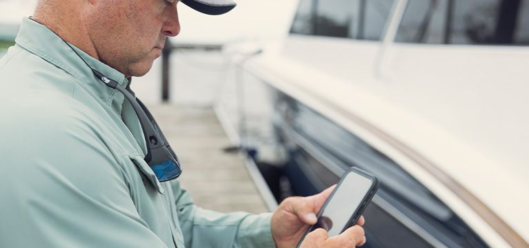 Cat customer looking at his phone next to a boat on a dock