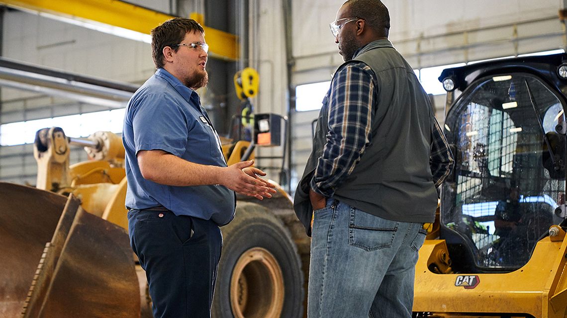 2 people speaking to each other; machine in the background