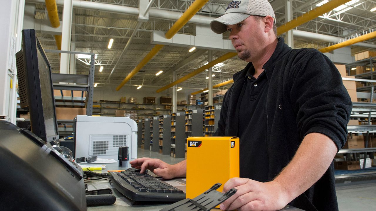 Cat dealer worker fulfilling a parts order at a computer