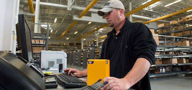Cat dealer worker fulfilling a parts order at a computer
