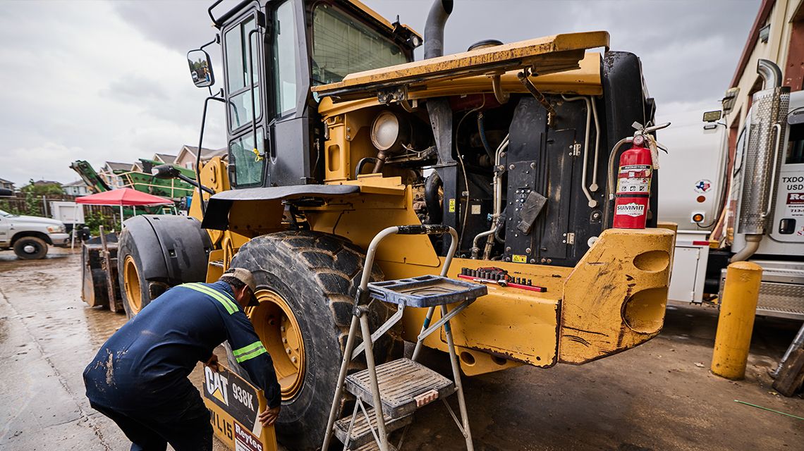 an operator inspecting the tire of a machine