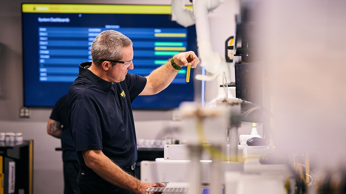 a technician running some tests, holding a vial